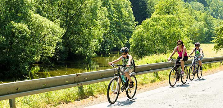 Machen Sie schöne Fahrradtouren im Urlaub und erleben Sie die Natur auf eine neue Weise Mutter und Tochter auf einem Fahrradweg mit Gebüsch im Hintergrund