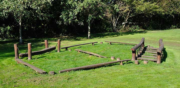 Besuchen Sie die spannenden Naturspielplätze und toben Sie sich richtig an den Spielgeräten im Wald aus Kinder sind um ein Spielgerät auf dem Naturspielplatz im Wald versammelt