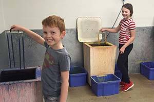 Het is leuk om zelf kaarsen te maken! Twee kinderen maken een kaars