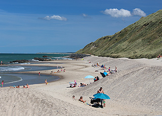 The lovely sandy beach with bathing guests by the high cliff in Lønstrup The lovely sandy beach with bathing guests by the high cliff in Lønstrup