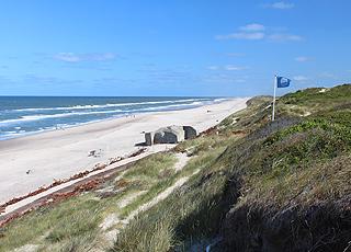 Det blå flag vajer over Søndervigs sandstrand med bunkere og dejligt badevand Det blå flag vajer over Søndervigs sandstrand med bunkere og dejligt badevand