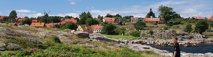 Aussicht von den Felsen hinter Svaneke Räucherei auf die Häuser Svanekes, Utzons Wasserturm und eine Mühle Aussicht von den Felsen hinter Svaneke Räucherei auf die Häuser Svanekes, Utzons Wasserturm und eine Mühle