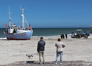 One of the fishing boats is being pulled up on the beach by a tractor in Thorup Strand One of the fishing boats is being pulled up on the beach by a tractor in Thorup Strand