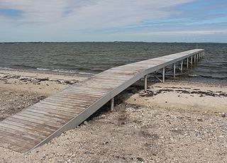 Lång badbrygga vid stranden i sommarstugeområdet Vinderup Lång badbrygga vid stranden i sommarstugeområdet Vinderup
