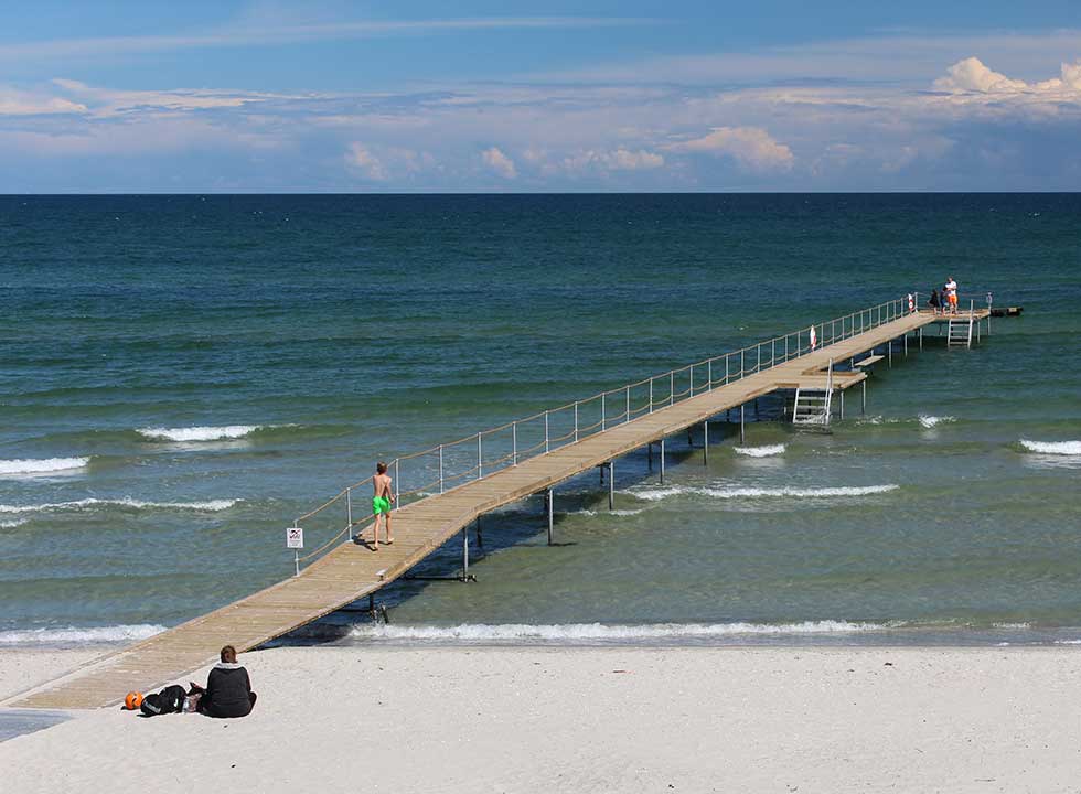 Lang badebro ved den brede sandstrand med klitter i Bratten Lang badebro ved den brede sandstrand med klitter i Bratten