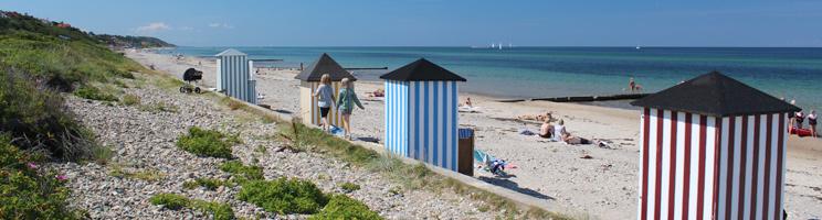 En sommerdag på den dejlige badestrand med charmerende badehuse i Rågeleje En sommerdag på den dejlige badestrand med charmerende badehuse i Rågeleje