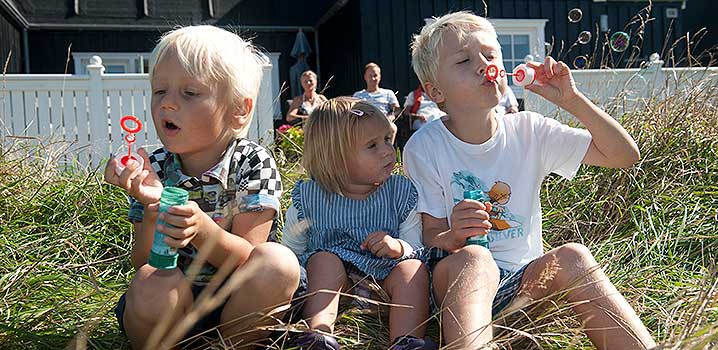 Kinder pusten Seifenblasen im Ferienhaus Familie im Ferienhaus genießt das Wetter