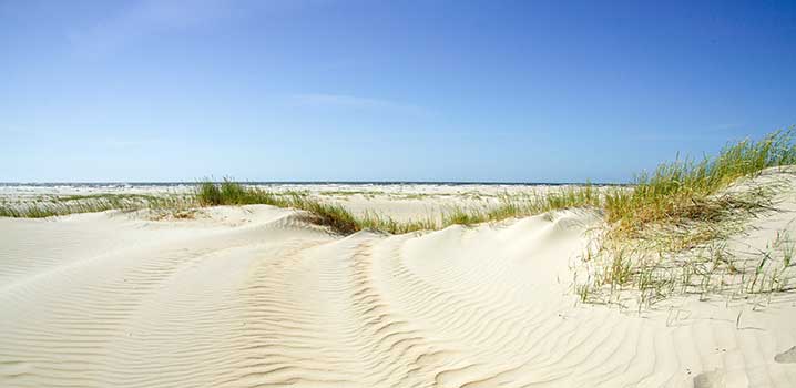 Sandige Dünen und ein Meeresblick soweit das Auge reicht. schoenste-orte-daenemarks-sandduene-mit-meer-und-blauem-himmel