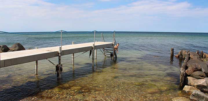 Steinstrand mit Badesteg Junge badet im Wasser am Gilleleje Strand