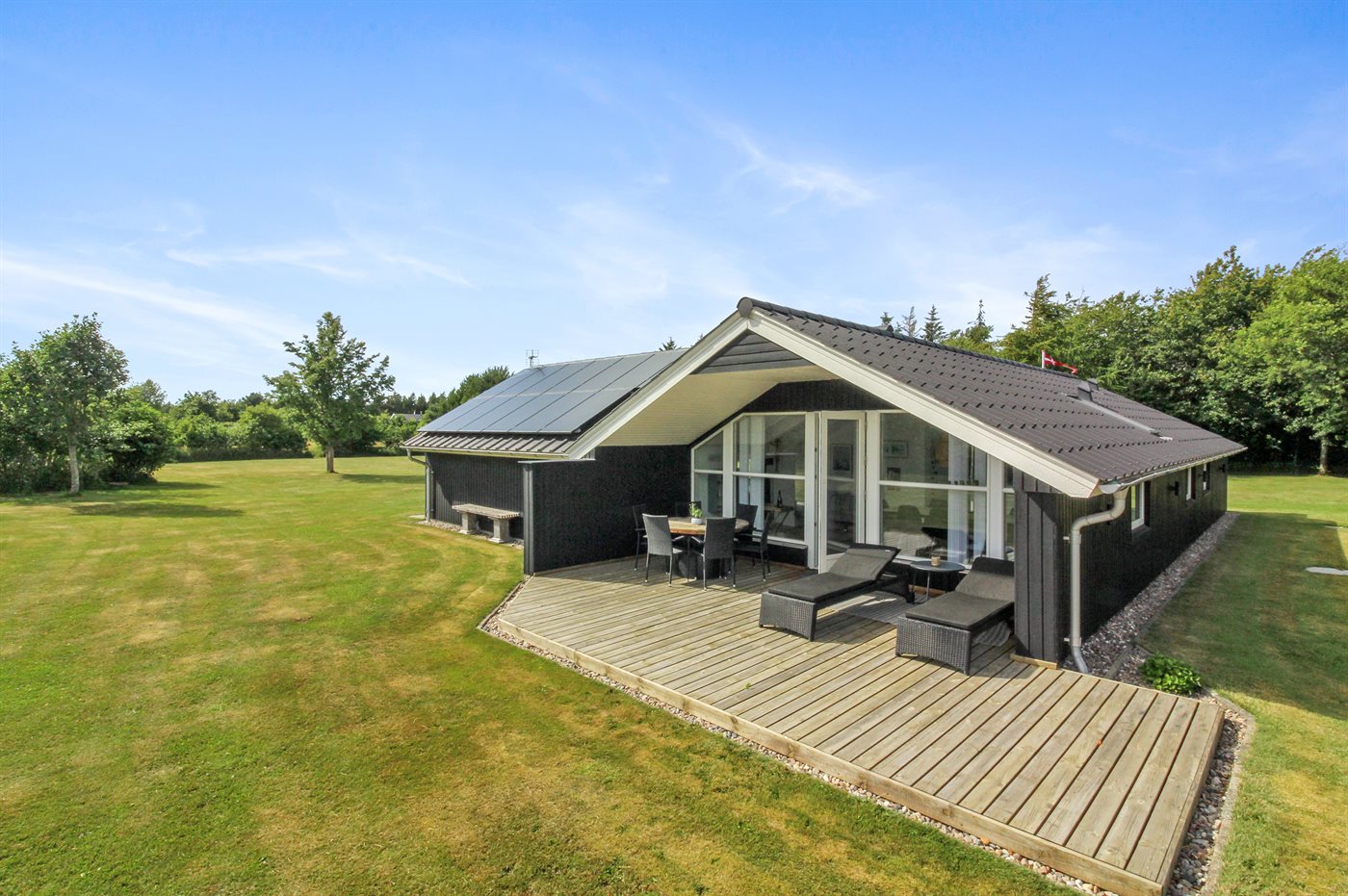 Ein kleines rotes Haus steht auf einem grasbewachsenen Hügel am Meer.
