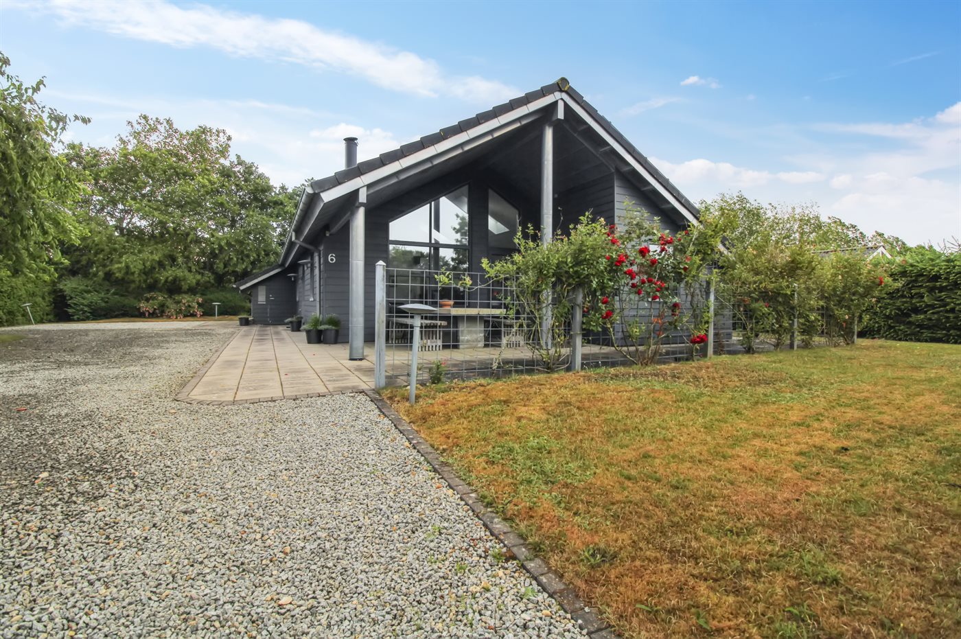 Ein kleines rotes Haus steht auf einem grasbewachsenen Hügel am Meer.