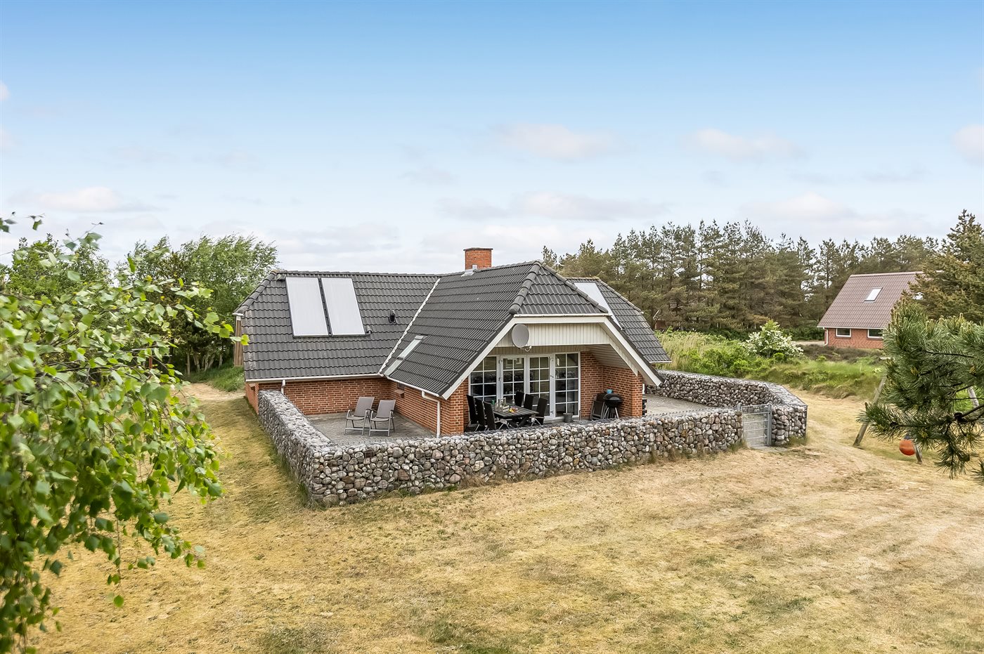 Ein kleines rotes Haus steht auf einem grasbewachsenen Hügel am Meer.