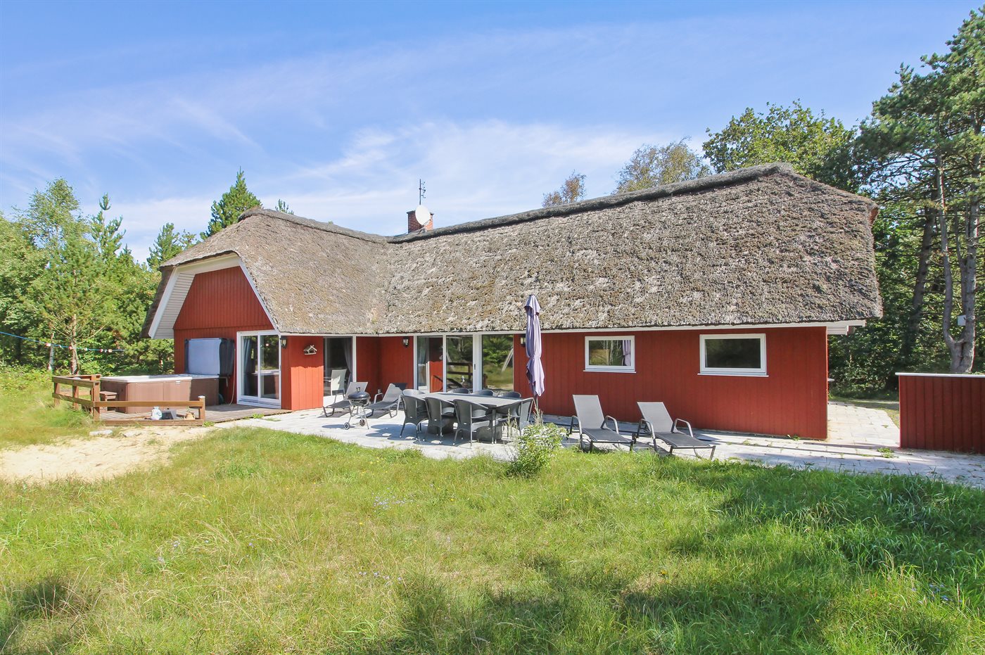 Ein kleines rotes Haus steht auf einem grasbewachsenen Hügel am Meer.