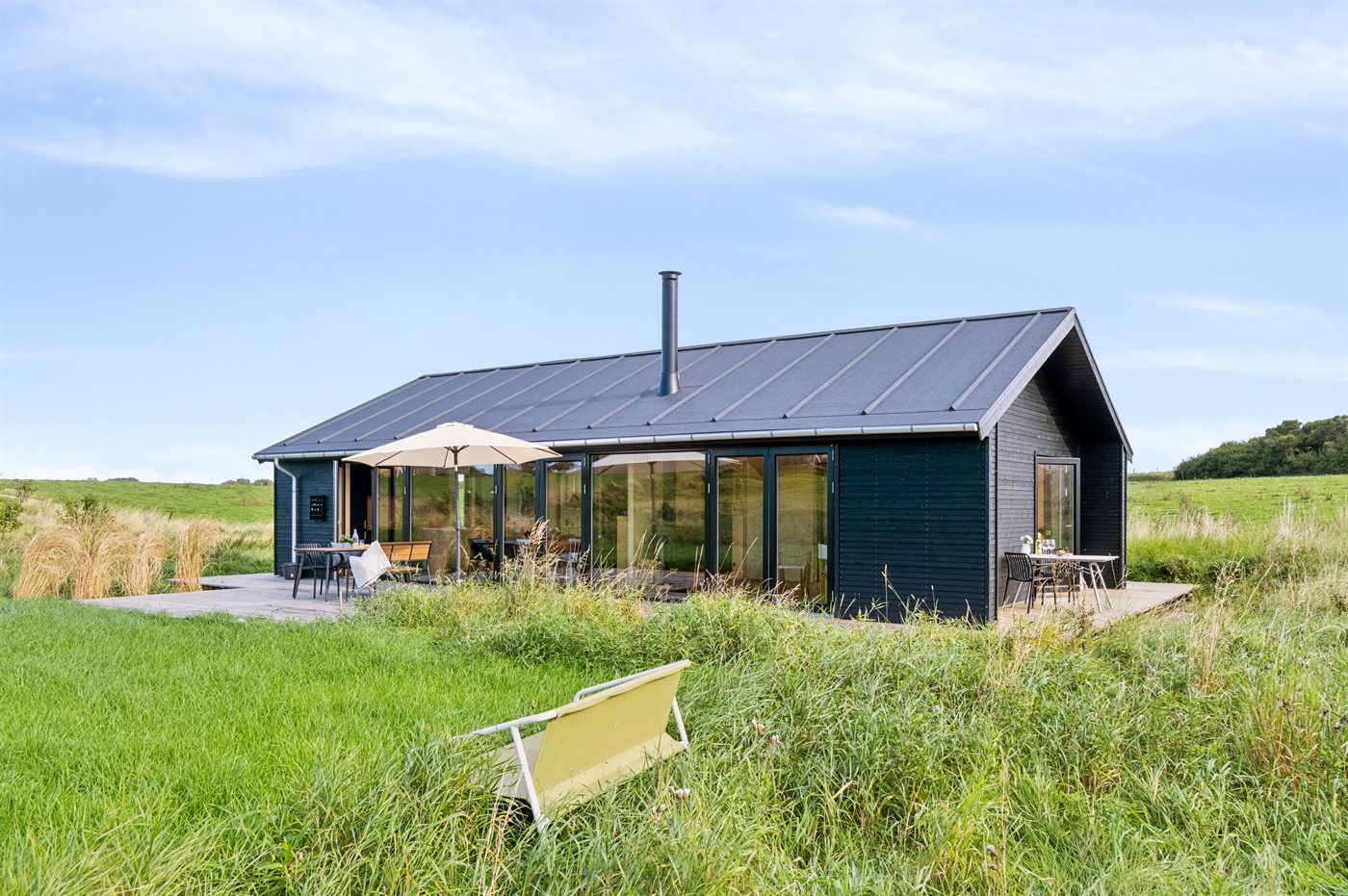 Ein kleines rotes Haus steht auf einem grasbewachsenen Hügel am Meer.