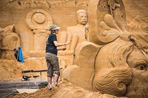 Oplev de fantastiske figurer formet i sand Kvinde arbejder på en sandskulptur