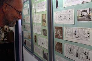 Den samhällssatiriska tecknade serien 'Livets gang i Lidenlund' studeras Museumsgäst tittar på utställning