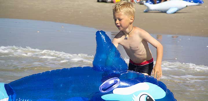 Junge mit Strandspielzeug am Strand