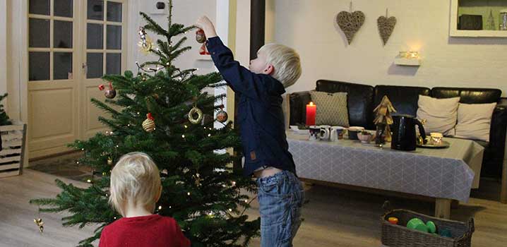 Kinder schmücken den Weihnachtsbaum im Ferienhaus