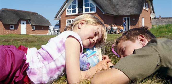 Barn kopplar av i gräset framför sommarstugan